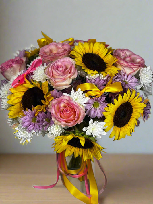 Bouquet of flowers with sunflowers, roses, and daisies on a gray background