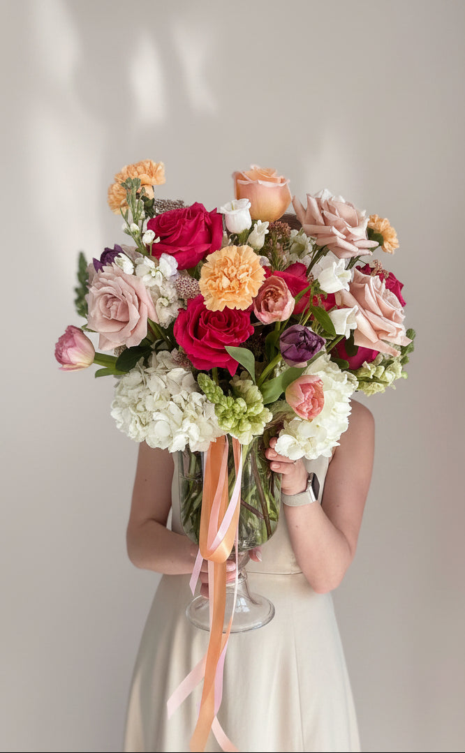 Woman holding a large bouquet of flowers against a plain background